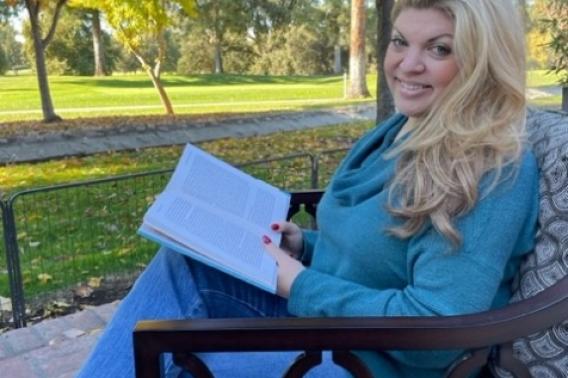 Patient Gina Arata reads on a bench