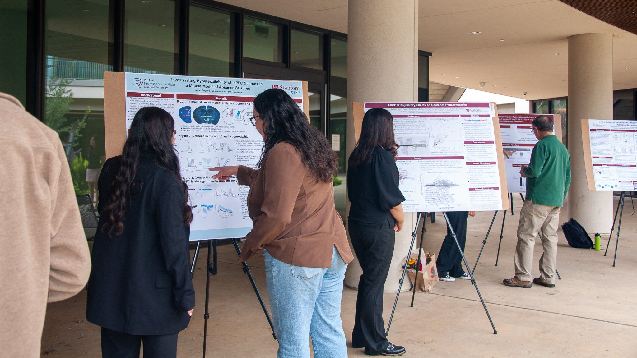 Valerie Vargas-Zapata, Diversity Initiatives Program Coordinator, learns about a student's research project at the 2024 NeURO and NeURO-CC poster session