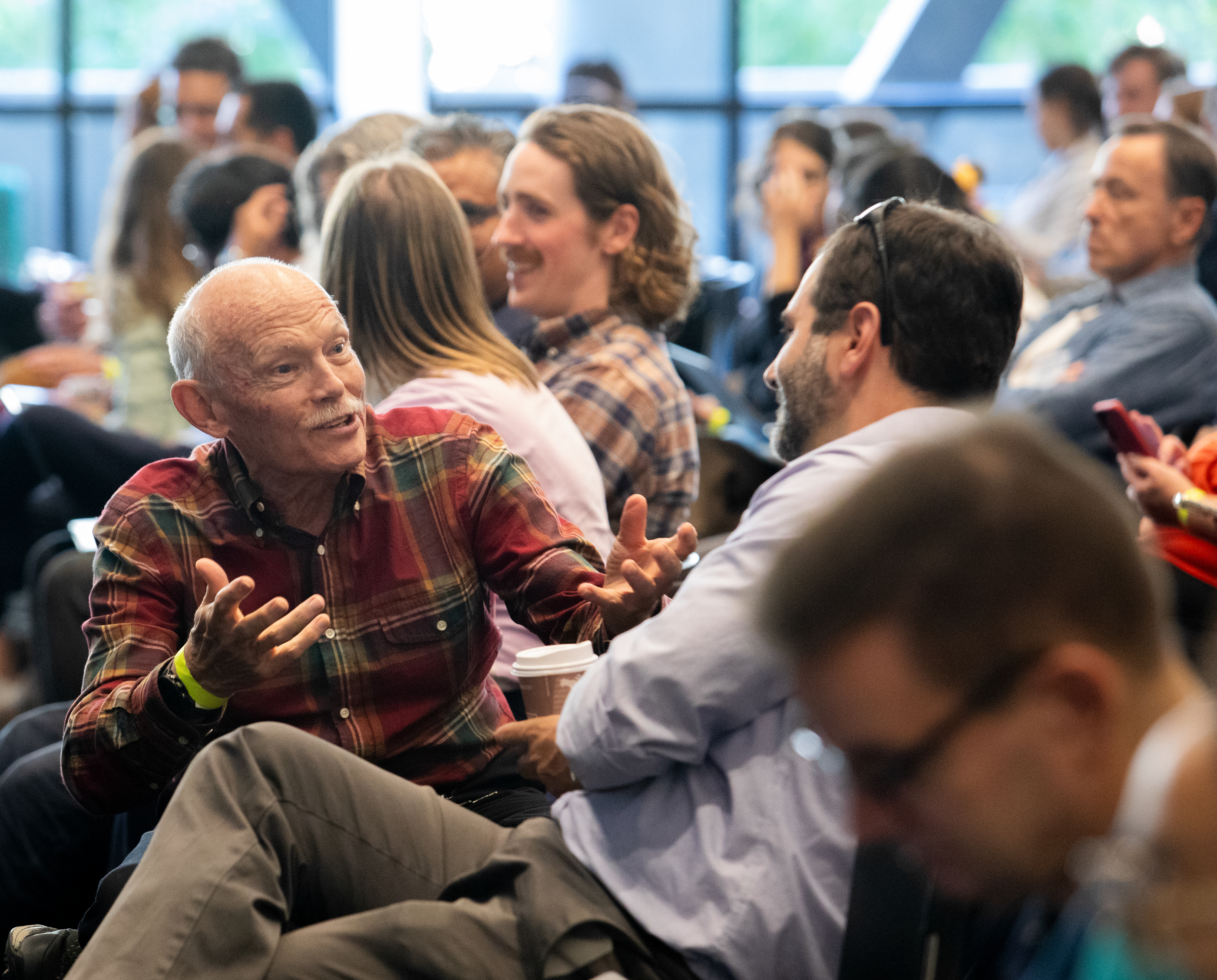 Cognitive scientist Jay McClelland speaks animatedly to a colleague in the audience of Wu Tsai Neuro's 2024 Symposium