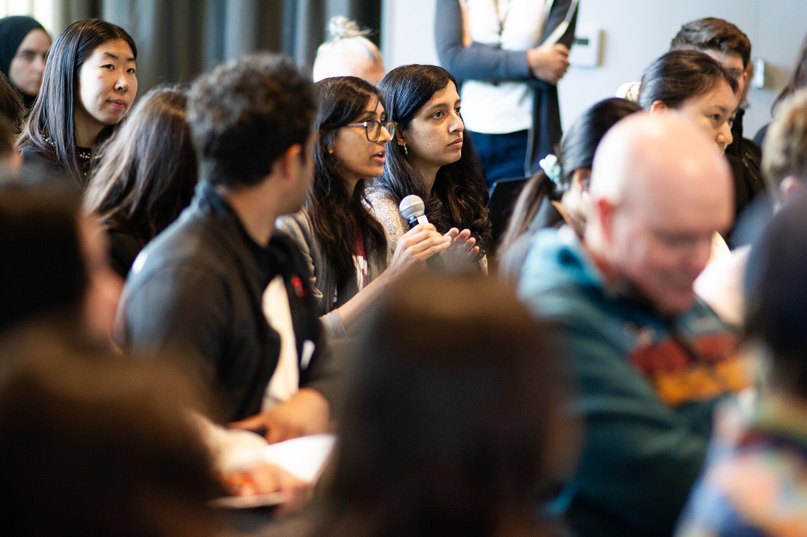 An audience member holding a microphone asks a question.
