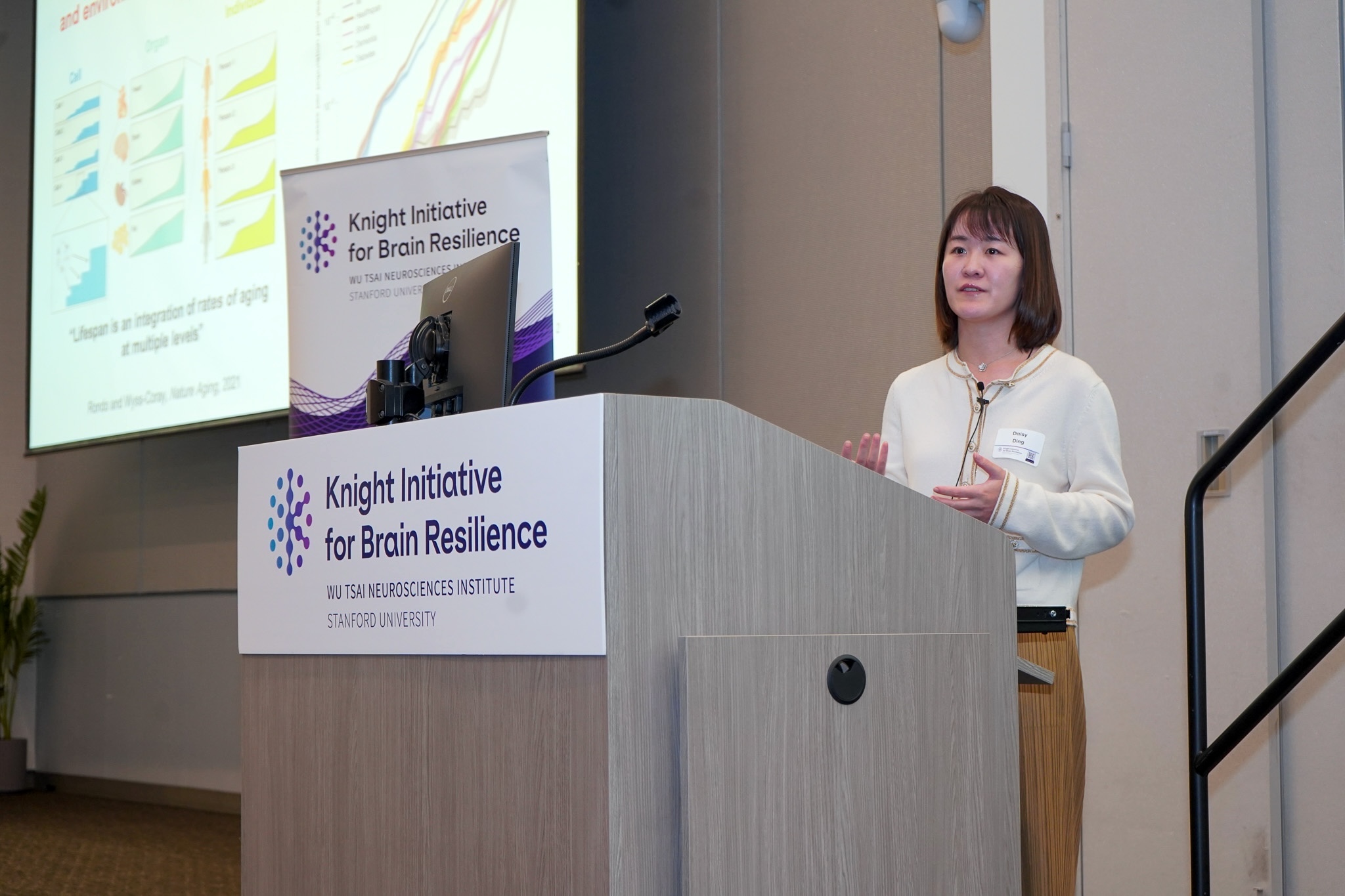 Daisy Ding speaks at a lectern.