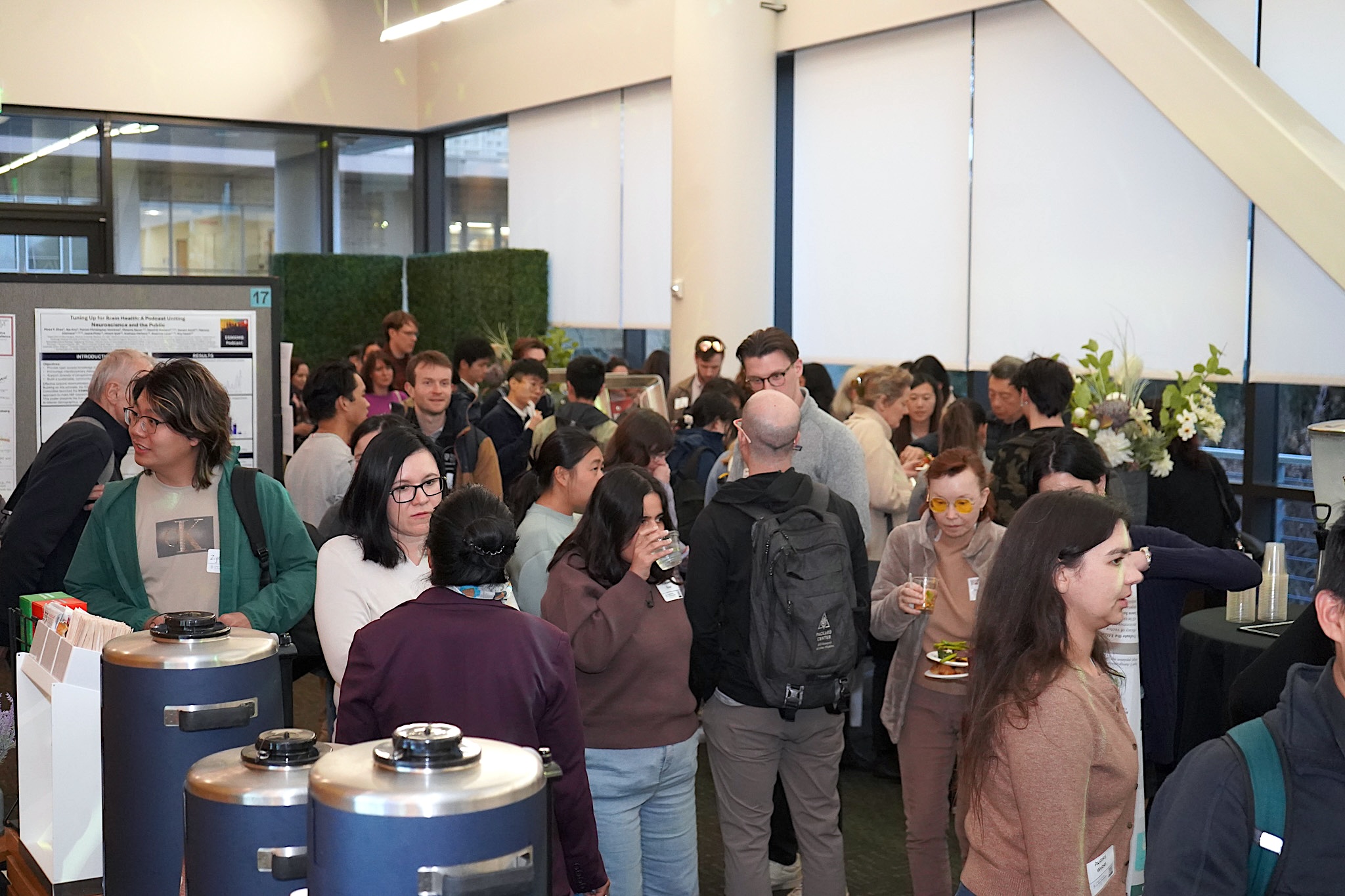 A crowd of people speaking to each other near scientific posters. 