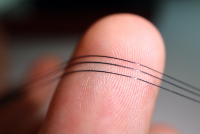 Neurostring fibers stretched against a researcher's finger