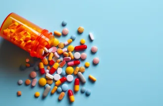 A orange bottle of colorful pills spilled on a blue background