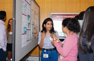 Marwa Zafarullah talks about her research poster with another person.