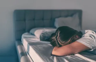 A person sleeping face down on a bed during there day.