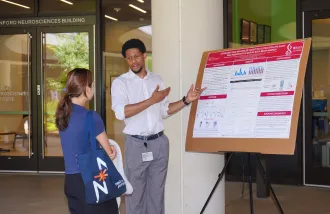 Samuel Egboh talks about a research poster with another person.