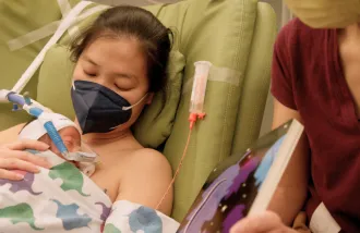 A mother holds her newborn baby in a hospital bed. 