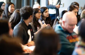 An audience member holding a microphone asks a question.