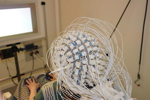 A participant wearing the OPM sensor helmet whilst looking at visual stimuli on the screen in the Koret HNCL