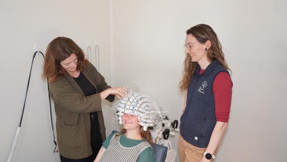 Two researchers preparing a participant for an OPM-MEG session in the Koret HNCL
