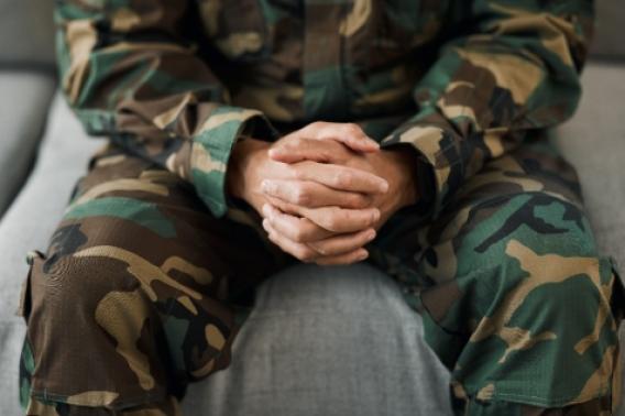 Image of veteran with their hands in their lap sitting on a couch
