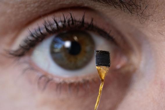 A close up of someone holding a microchip up to their eye