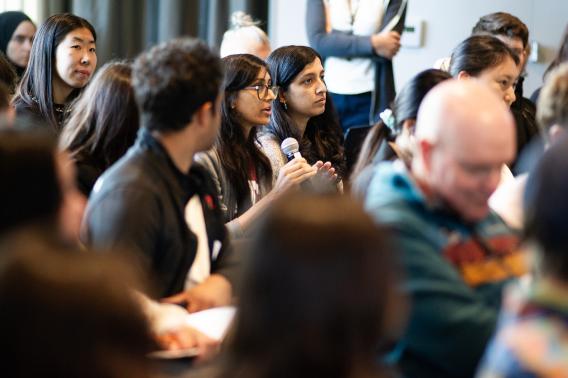 An audience member holding a microphone asks a question.