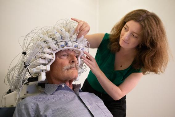 A woman adjusts a helmet-like apparatus on a man's head