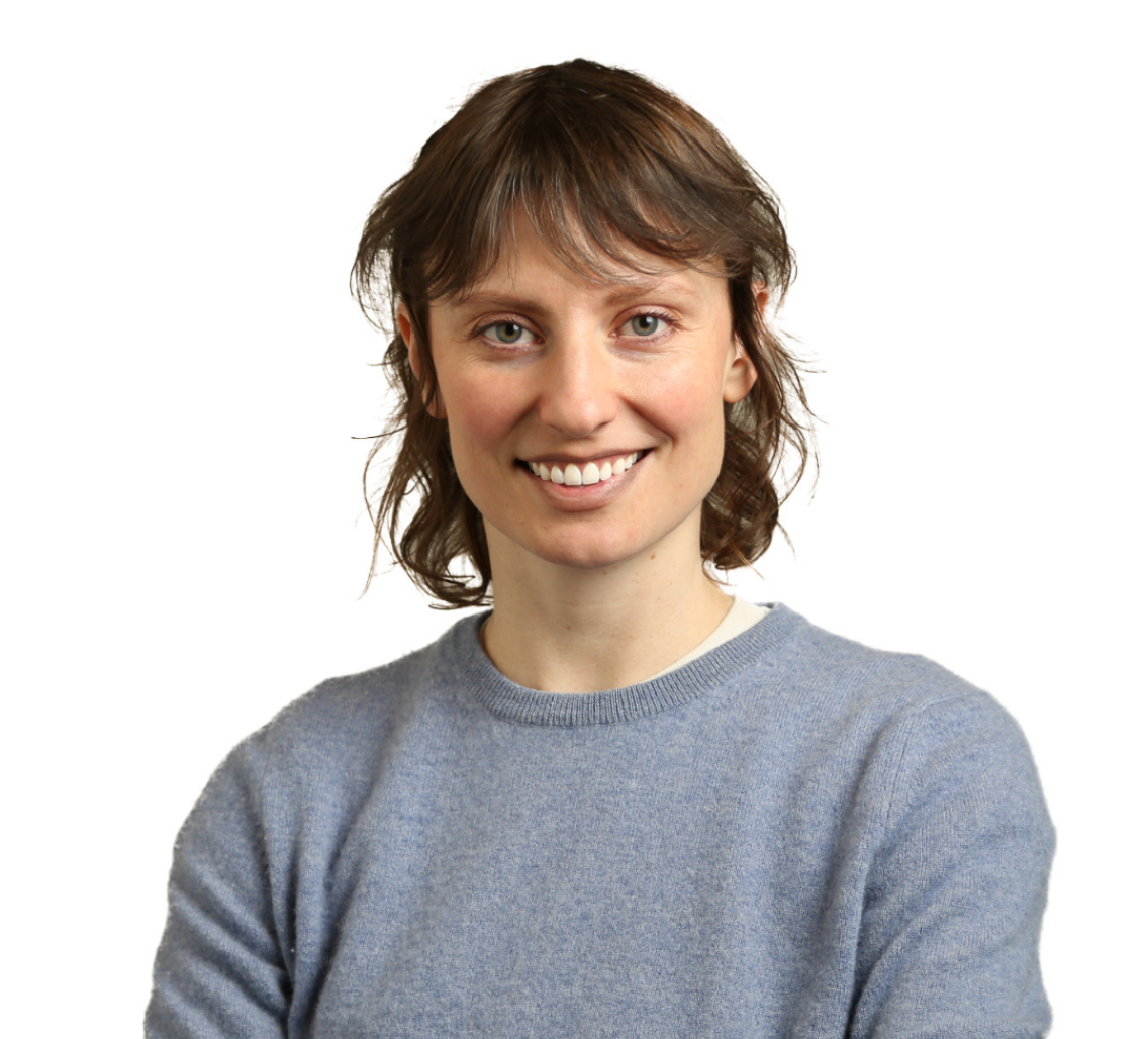 Dr. Laura Driscoll, wearing a grey sweater, smiles at the camera in front of a white background.
