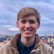 Chase smiles at the camera in front of a cloudy-sky background